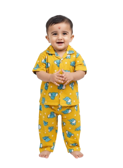 Smiling baby in yellow elephant print pajamas, standing barefoot against white background