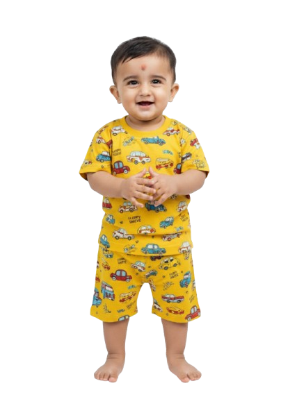 Smiling baby in yellow kids pajamas with colorful car print, standing barefoot